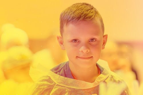 Uśmiechnięty chłopiec w wieku około 7 lat w ubraniu ochronnym.