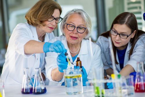 Edukatorka tłumaczy dwóm kobietom reakcje chemiczne