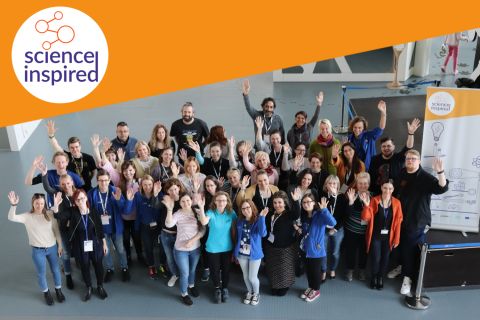 Grupa osób pozuje i macha do zdjęcia, w rogu zdjęcia logo Science Inspired