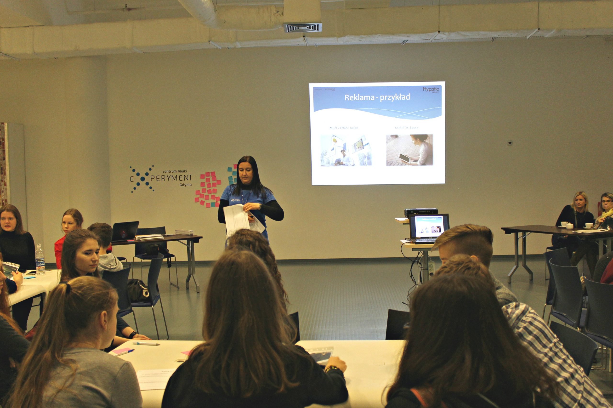 Kobieta prowadzi wykład przed grupą młodzieży