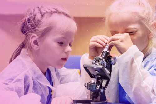 Dwa przedszkolaki bawią się mikroskopem.