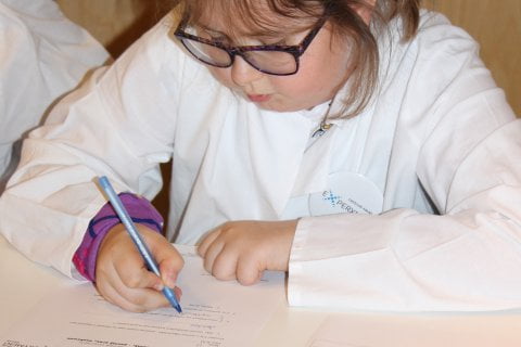 Dziewczynka w okularach zapisująca coś na kartce