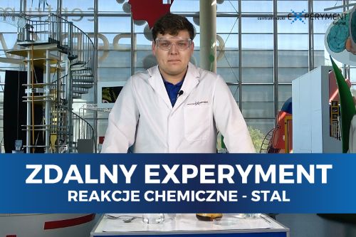 Zdalny experyment, reakcje chemiczne stal. Edukator stoi przed blatem ze sprzętem chemicznym.