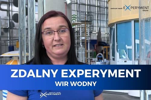 Zdalny experyment, wir wodny. Edukatorka stoi na tle wystawy Hydroświat.