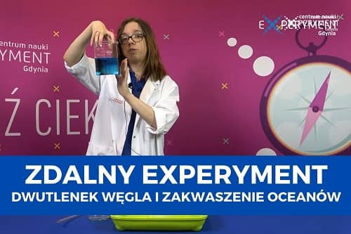 Miniaturka do filmu z cyklu ZDALNY EXPERYMENT pod tytułem Dwutlenek węgla i zakwaszenie oceanów. Na zdjęciu kobieta trzymająca zlewkę z niebieskim płynem.