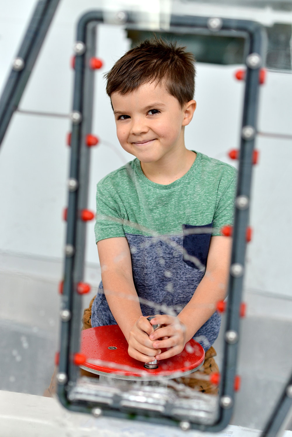 Na zdjęciu jest chłopiec w wieku około 7 lat na wystawie hydroświat w Centrum Nauki EXPERYMENT