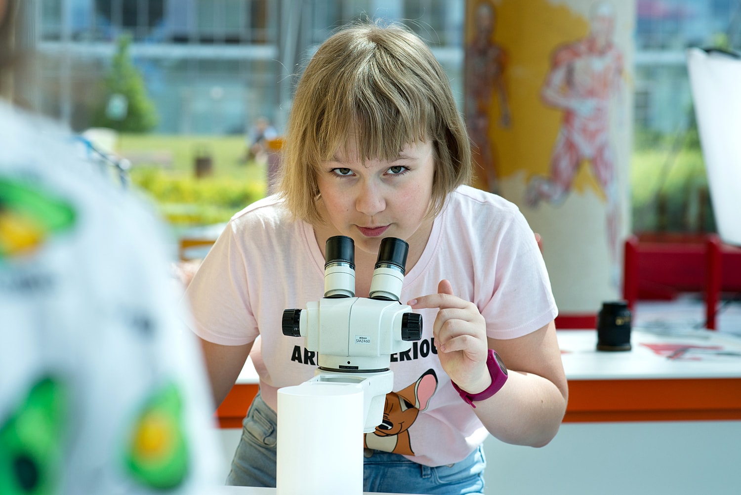 Na zdjęciu jest dziewczynka w wieku około 12 lat przy mikroskopie na wystawie w Centrum Nauki EXPERYMENT