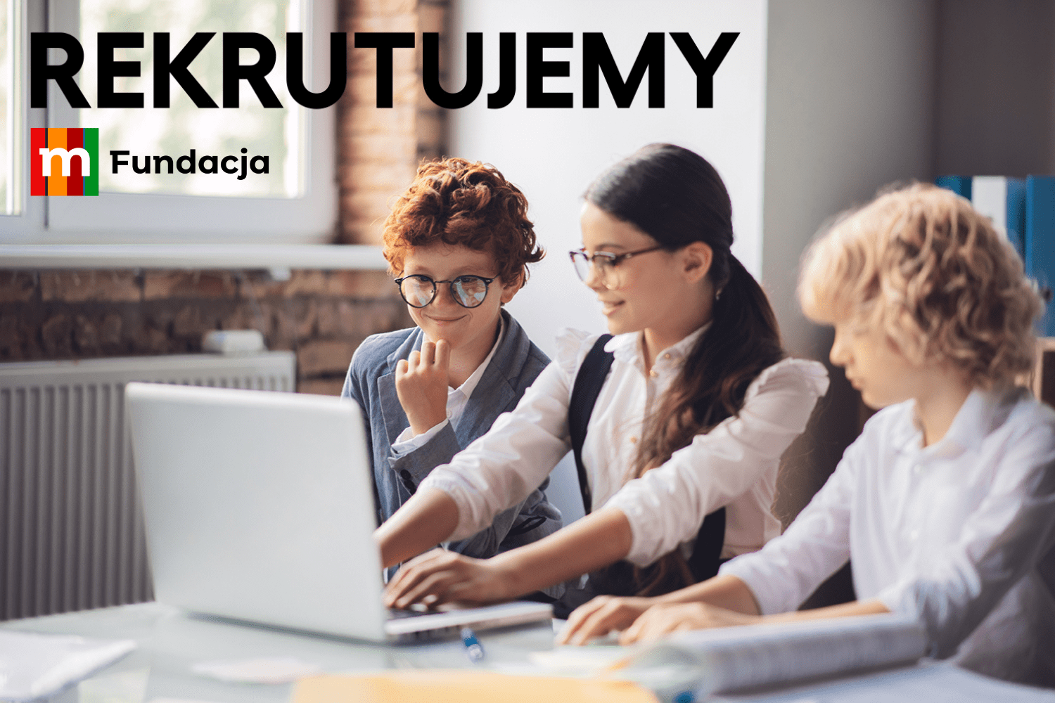 Na zdjęciu widać troje dzieci w wieku około 11 lat, które siedzę przy komputerze.