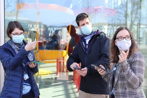 Trzy osoby w maseczkach z telefonami w dłoniach.