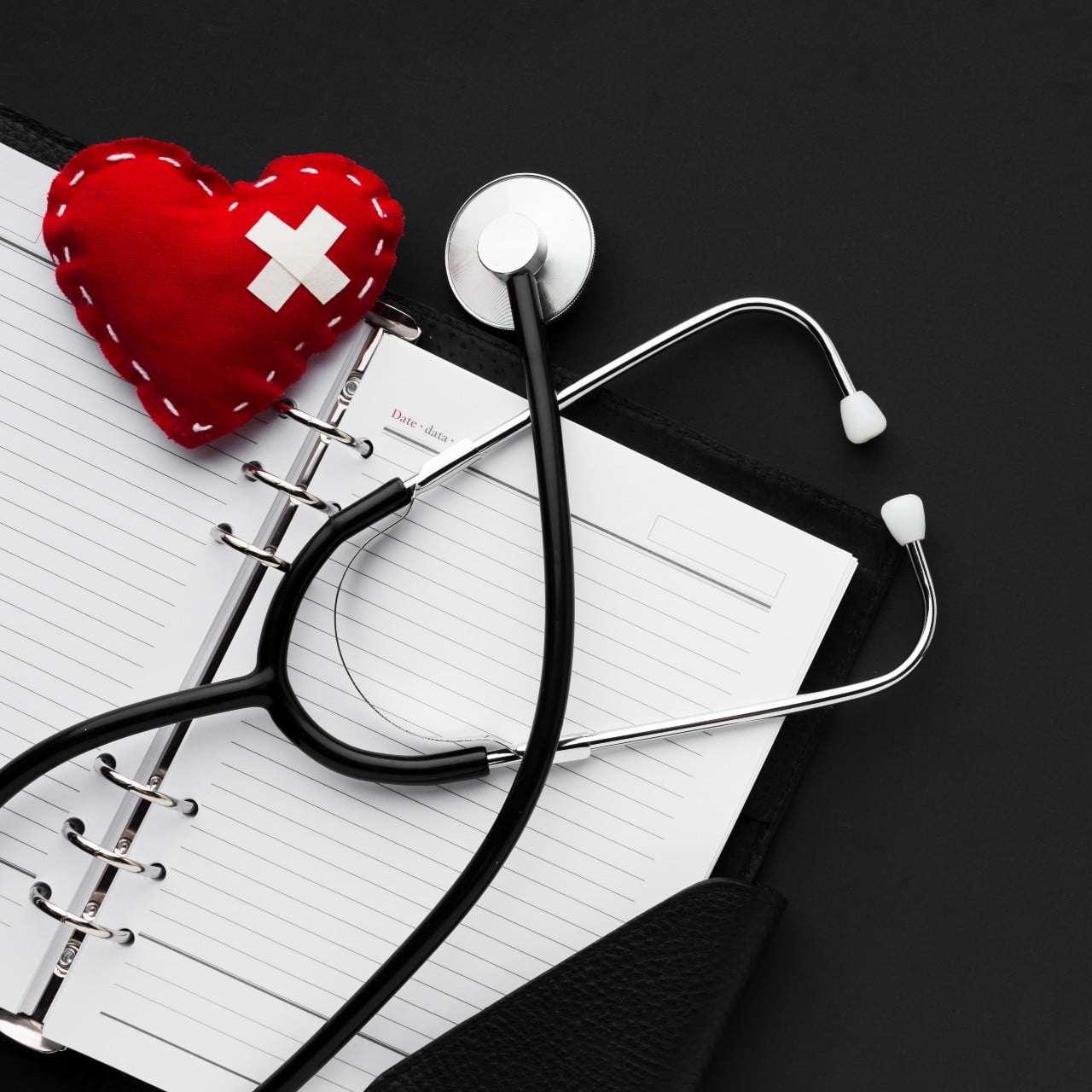 Stetoskop, notatnik i czerwone pluszowe serce.