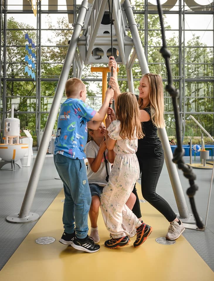 Zdjęcie grupy dzieci korzystających z atrakcji na wystawach Centrum Nauki Experyment razem z edukatorem CNE.