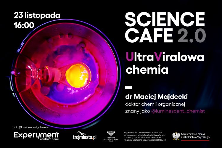 Kolorowa scena laboratoryjna ukazana z góry: w różowo-fioletowym świetle widać naczynie z fluorescencyjną cieczą i żółtą, świecącą kroplą