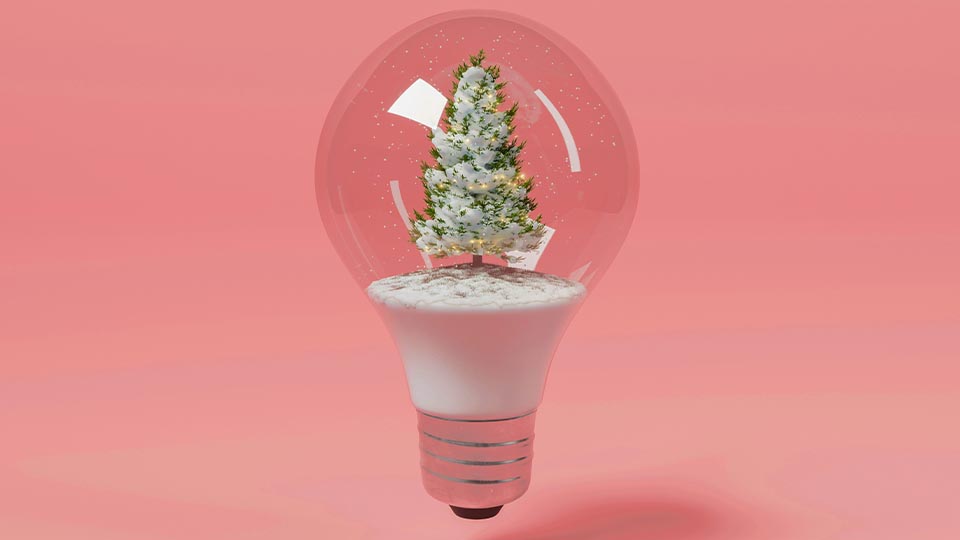Jak Experyment działa w grudniu? Żarówka na różowym tle z przyozdobioną świąteczną choinką w środku.