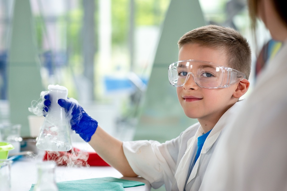 dziecko podczas zajęć edukacyjnych wykonuje doświadczenie z wykorzystaniem suchego lodu